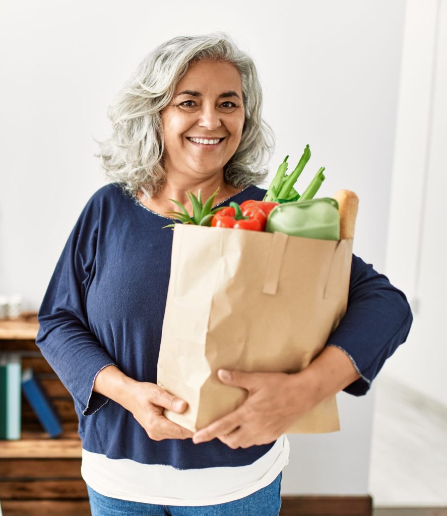 Woman holding grocery bag filled with produce.