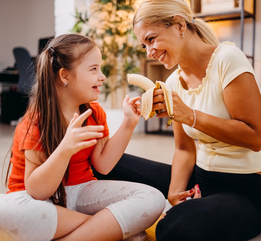Caregiver giving a girl a banana