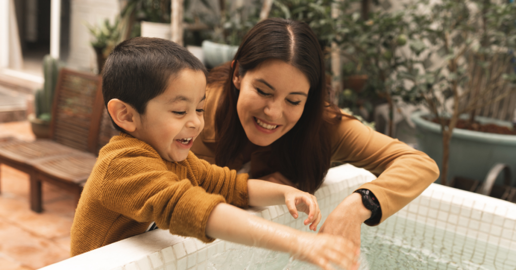 A parent and a child with autism play in water - Autism resources for families.