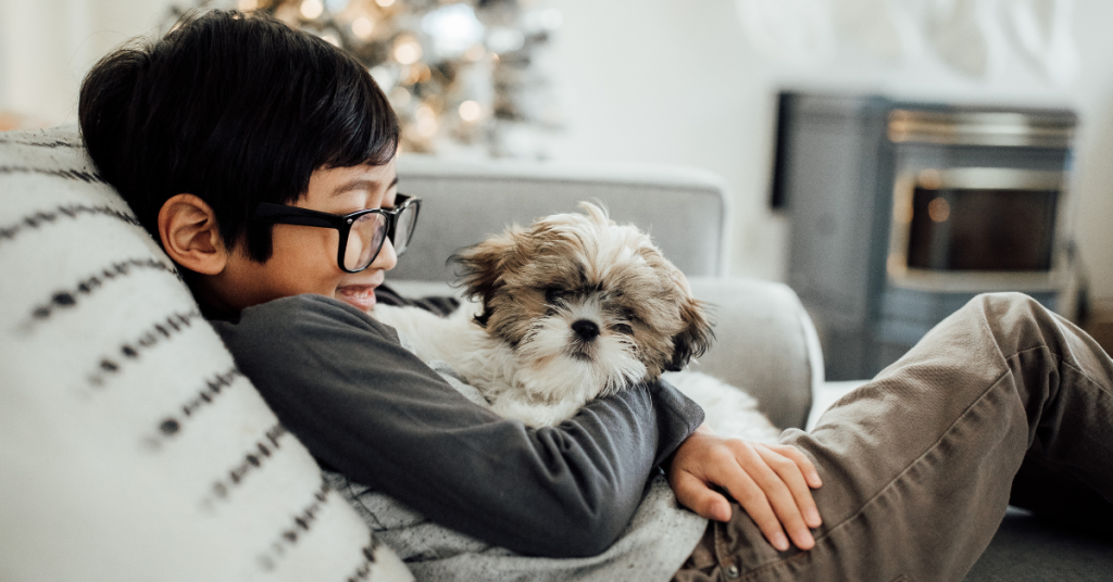 A child and dog sit together on a couch that shows Benefits of an Emotional Support Animal for Children with Autism.