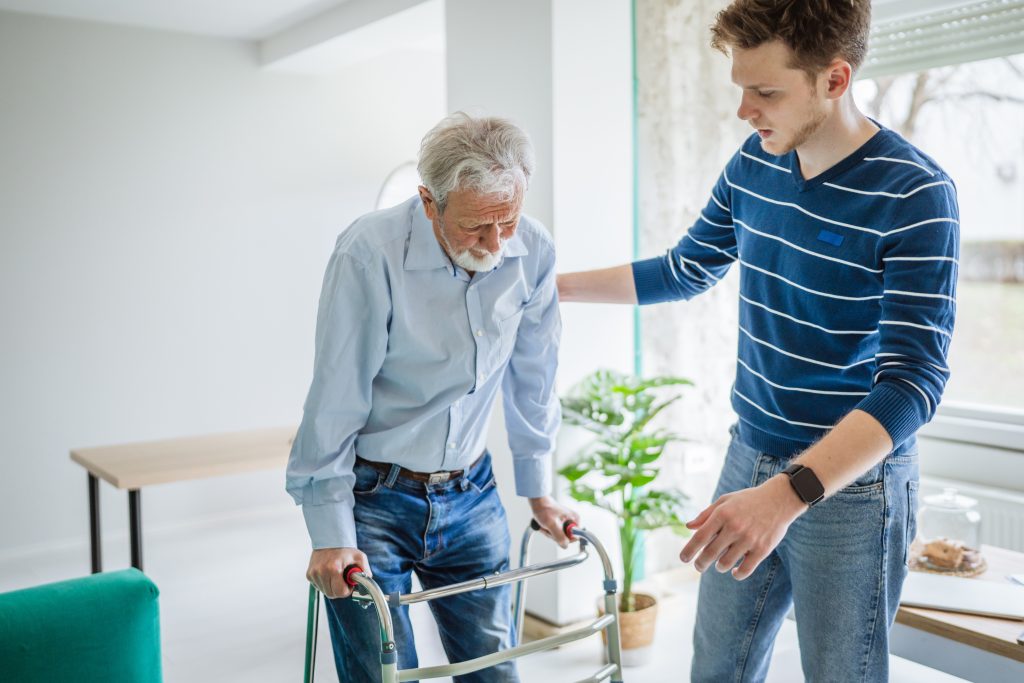 Grandson helping his Grandfather walking with a walker