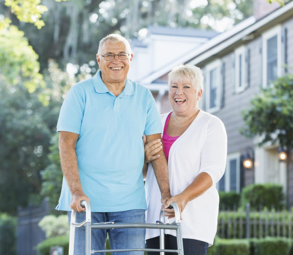 Happy couple walking with husband using a walker